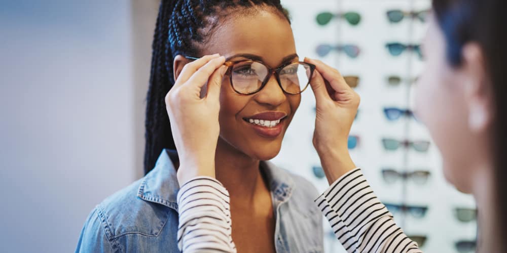 optician fitting prescription glasses to a lady, in an optician's shop