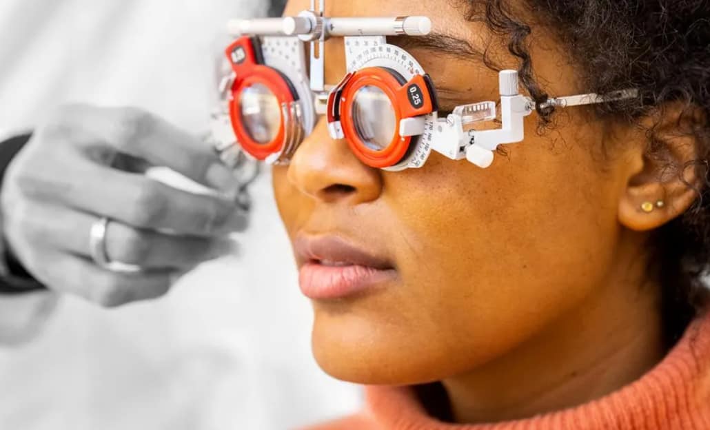 close up of woman having eyes tested. the optician's hand is shown adjusting eye testing equipment on the lady's face